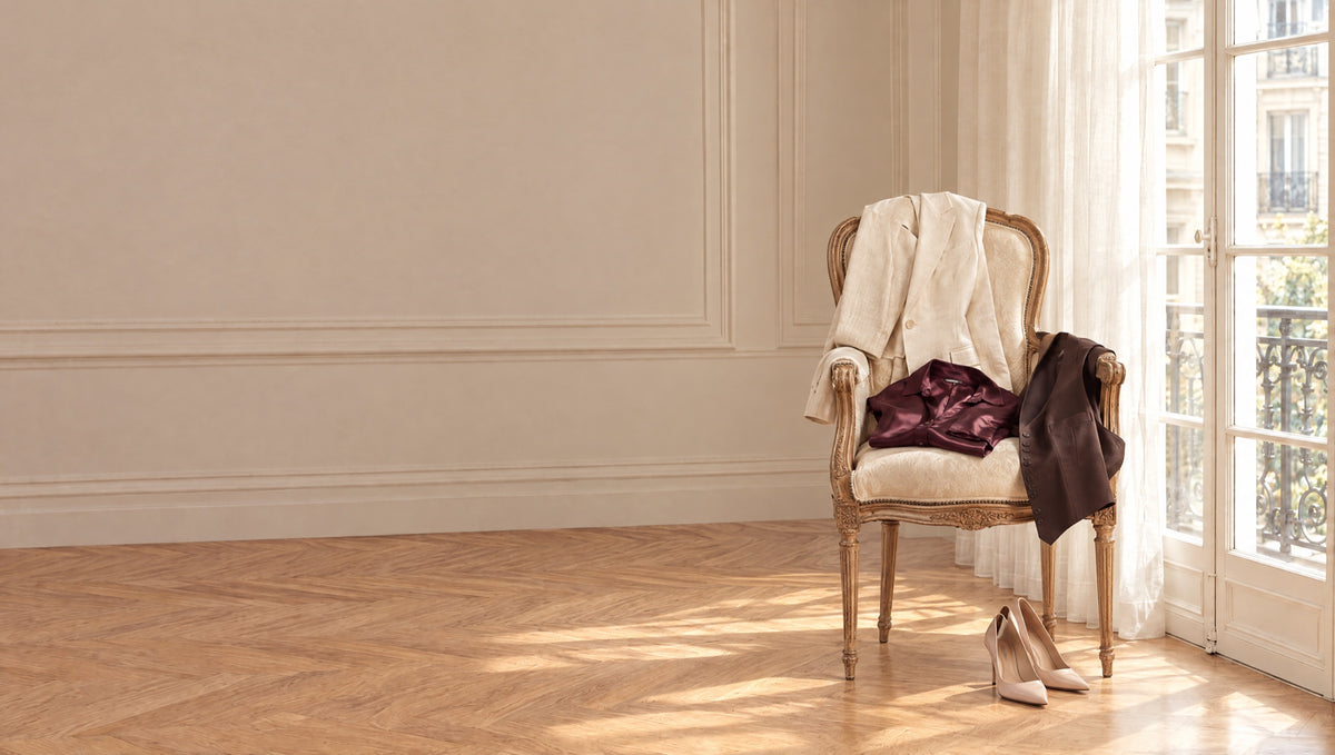 RUYA — pièces posées sur un fauteuil ancien, lumière rasante